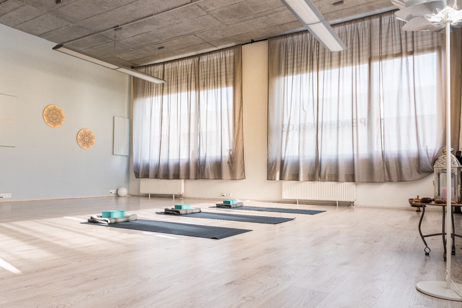 Prázdný sál jógového studia Peace Yoga s rozloženými podložkami a denním světlem z oken